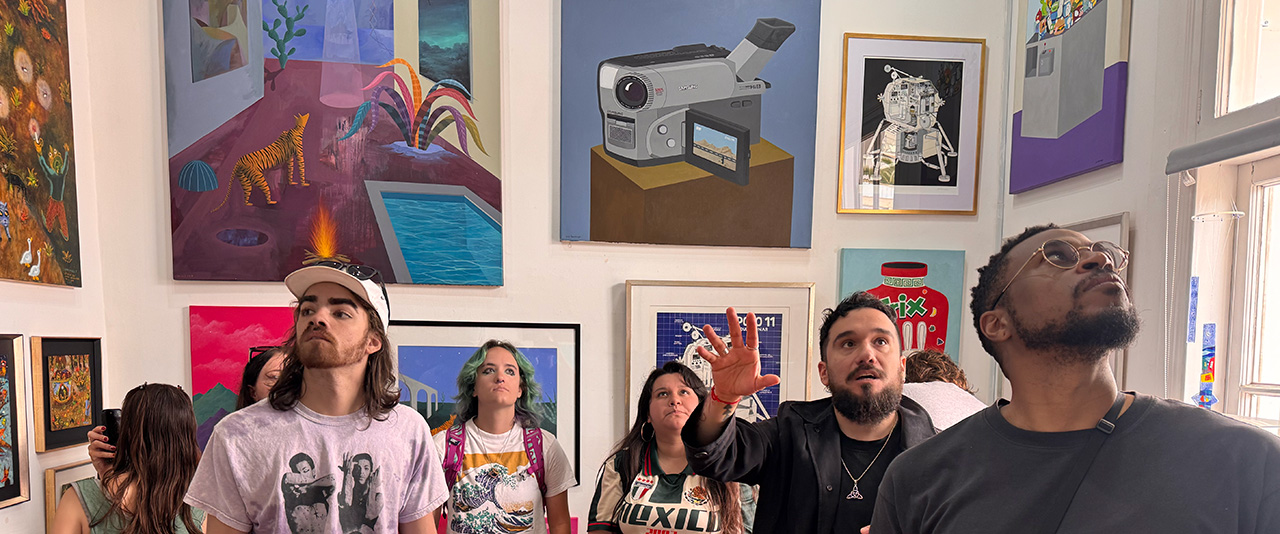 Three students, a gallerist and a professor inside a museum gallery filled with colorful contemporary paintings.