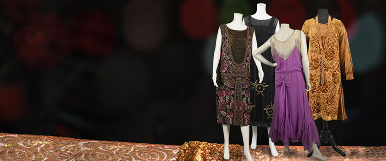Four mannequins on an orange carpet dressed in 1920s era dresses