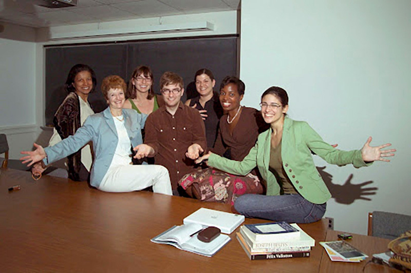 A smiling professor and students gather for a group photo.