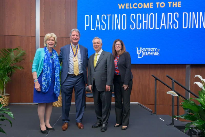 Debra Norris and UD Leadership standing in front of Plastino Scholars Dinner banner