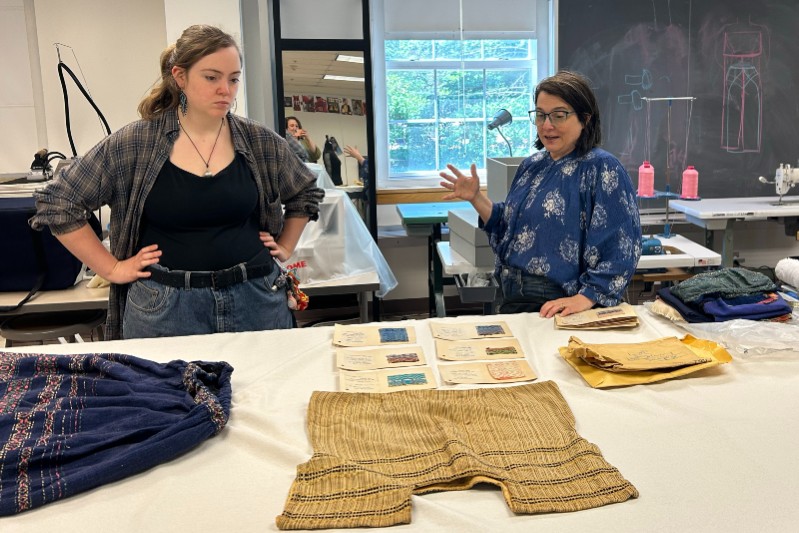 Two women looking at clothing material on a desk