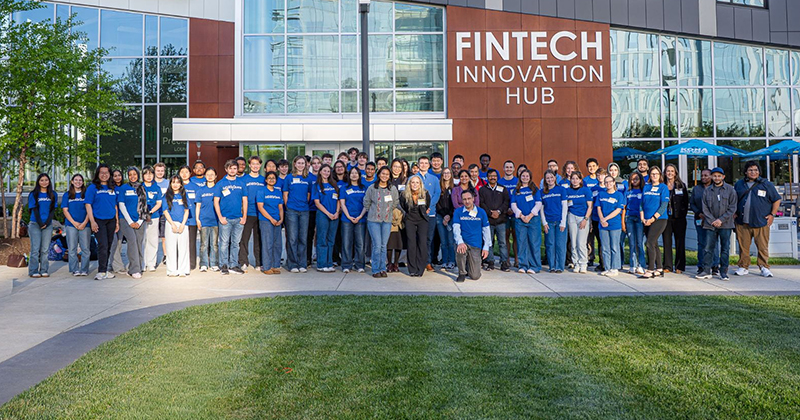 A large group of college students standing in front of the University of Delaware FinTech Innovation Hub building on the STAR Campus.