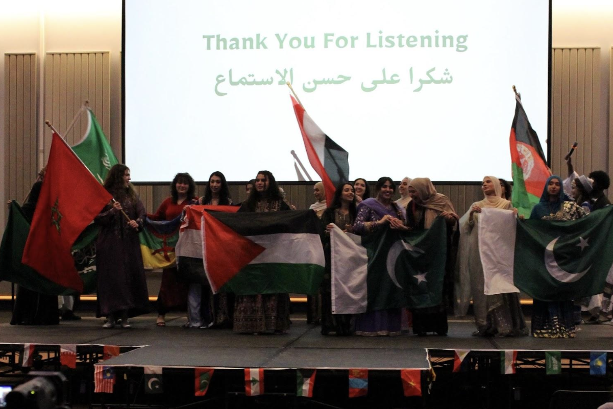 5 different colorful flags are displaed on stage at MESA's culture night. There is a sign that says thank you for listening.