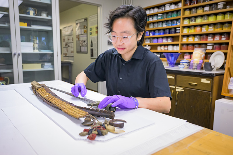 Student assessing the condition and materials of a sword and sheath.