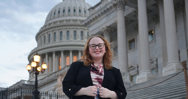 A college student in business attire in front of the U.S. Capitol building in Washington, D.C.