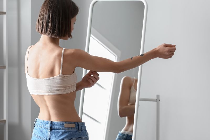 Woman looking in full length mirror 