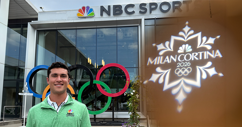 A smiling college student stands in front of the NBC Sports Building with the Olympic rings in front, with the Milan Olympics logo over a brown background partially covering the image