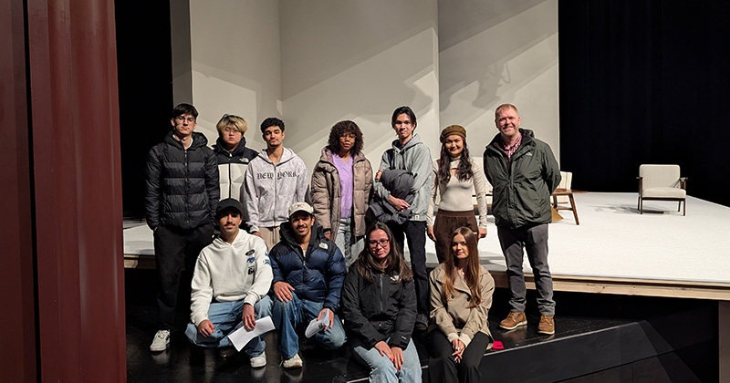 English Through Drama students smile with Phil Rice, assistant professor, while touring the Thompson Theater.