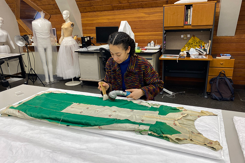 WUDPAC Fellow Allejandra Chavez performing a mechanical cleaning of the silk evening dress using a HEPA-filter equipped vacuum and brush. 