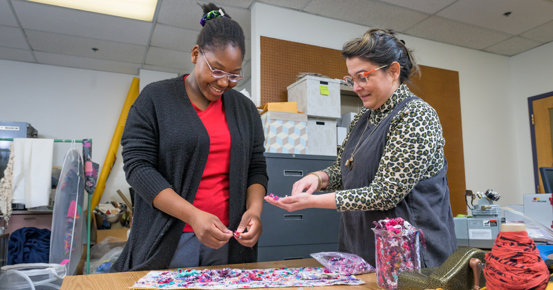 A college professor and student work on textiles in a laboratory.