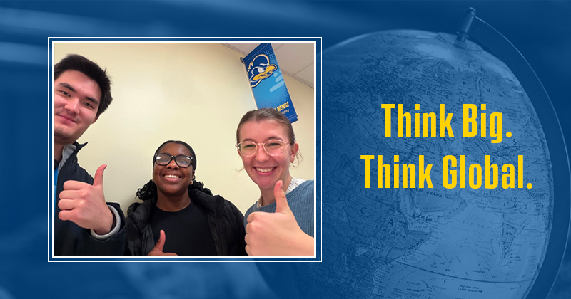 Photo of three college students with thumbs up over blue-screen image of globe and gold text: 