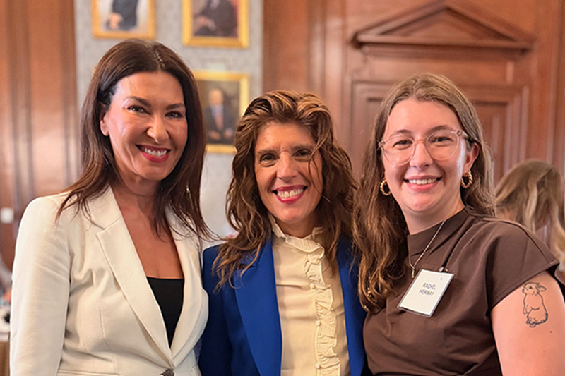 A smiling college student on the right in a group photo with a college professor and community leader