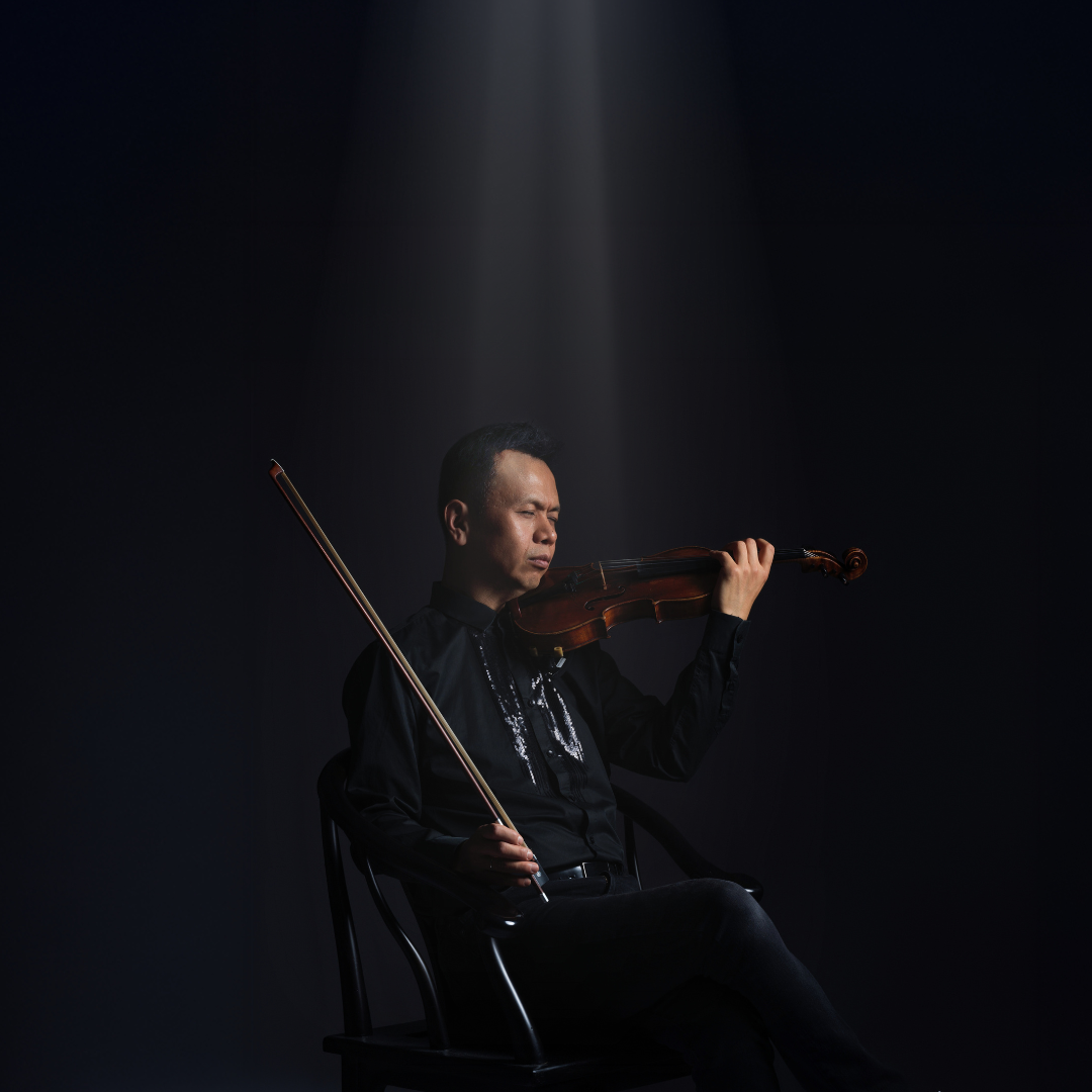 Musician on a stage sits in a chair and plays a musical instrument