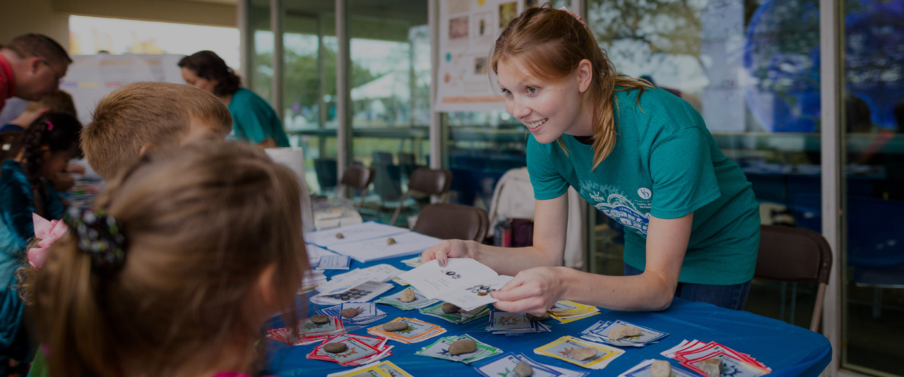 CEOE student interacts with childern at info table during Coast Day 2019