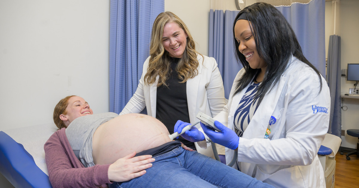Amanda Watson, assistant professor of nursing and director of the nurse-midwife program (left), and Doctor of Nursing Practice student Briana Abernathy (right) provide labor support for Jennifer Eldred, who is lying down and pregnant. 