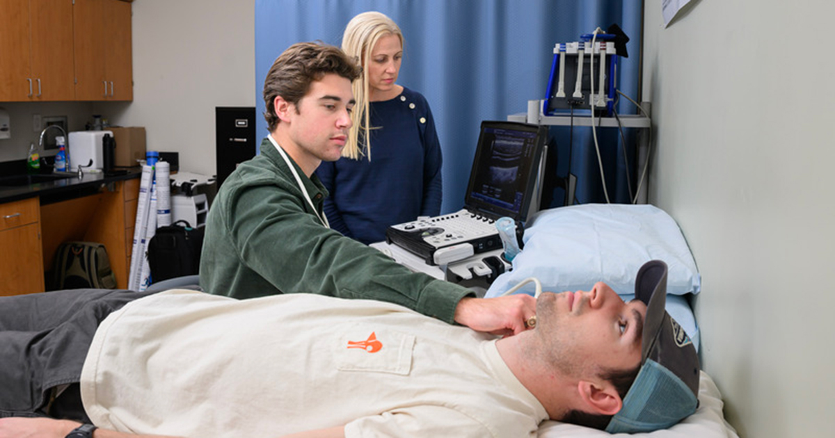 Grant Maxa, a senior human physiology major, demonstrates the scan of a carotid artery on with master’s student Evan Ciecko while KAAP Associate Professor Melissa Witman supervises.