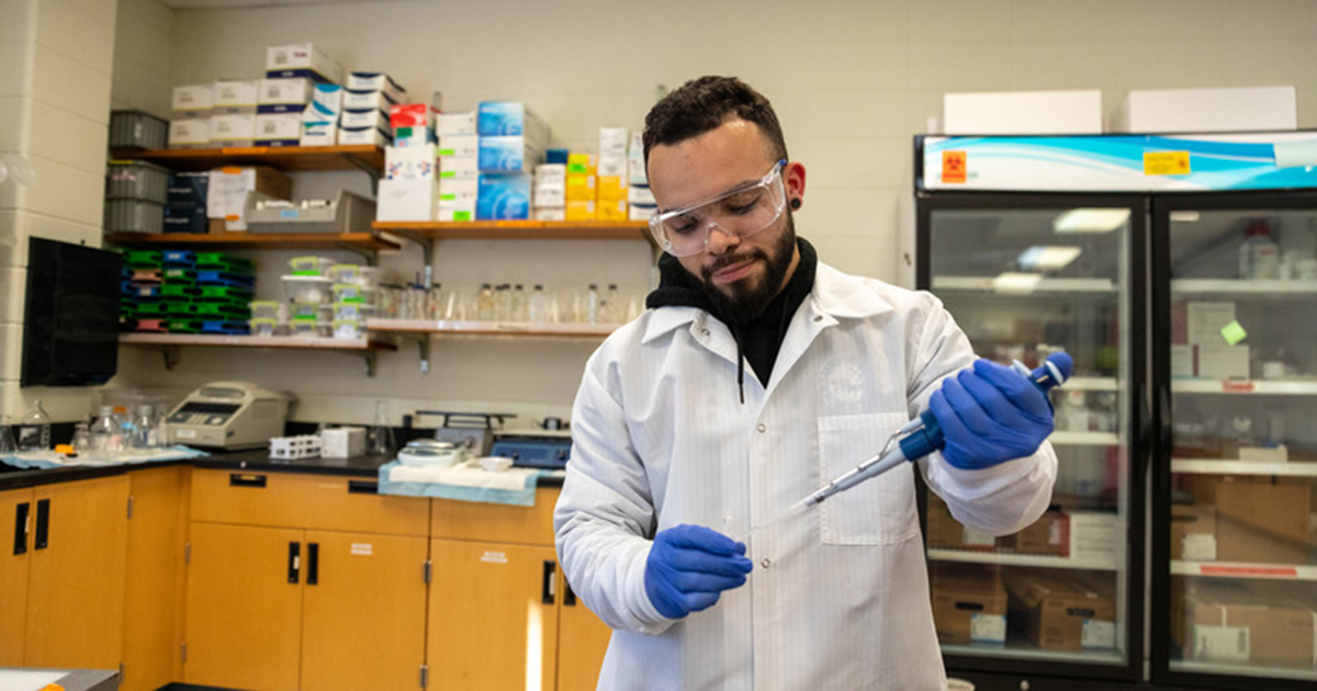 Medical science's master's student Jake Vargas-Peluso wears a lab coat, goggles and gloves as he works with a specimen in a Department of Medical and Molecular Sciences lab.