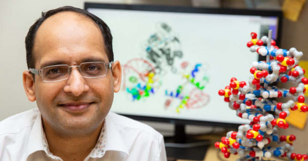 Vijay Parashar poses next to a 3-dimensional model of DNA