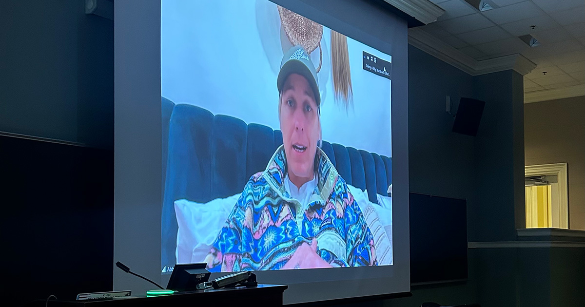 U.S. Soccer star Abby Wambach appears on a large projection screen at the front of a classroom, speaking to students virtually.