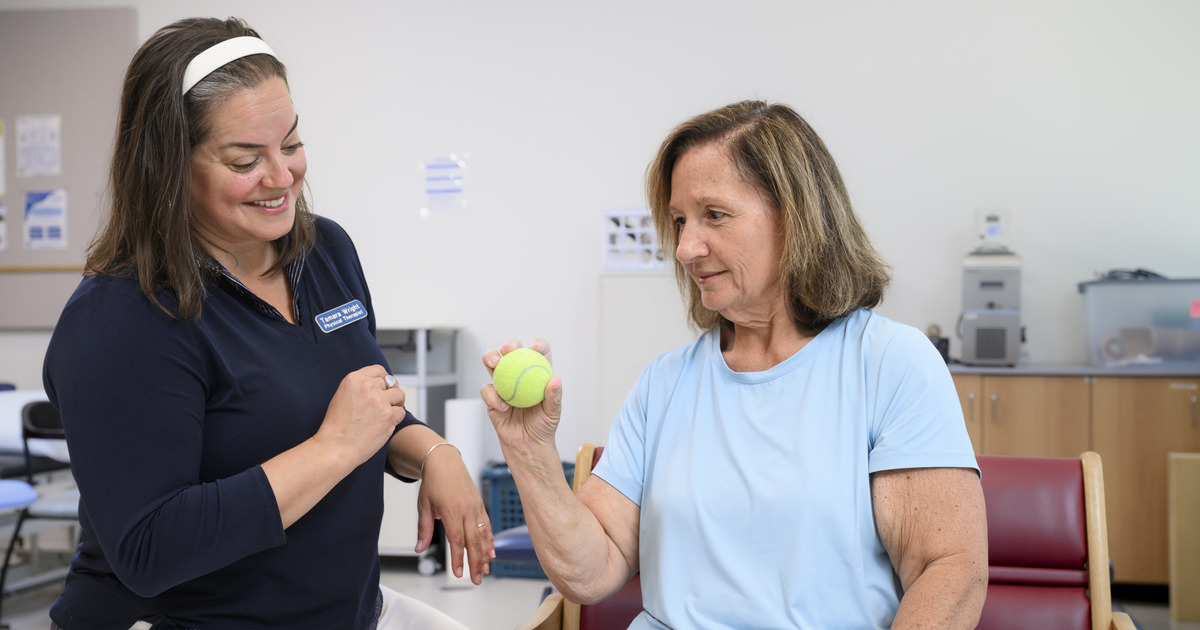 In this photo, research physical therapist Tamara Wright works with Angie Pellerito, a stroke survivor, on her grip. Here, Angie is grasping a yellow tennis ball.