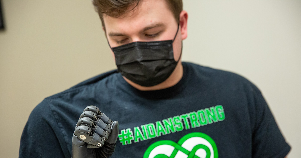 University of Delaware graduate Aidan Bradley makes a fist with his new bionic arm equipped with smart technology.
