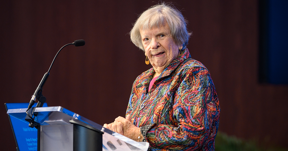 A photo of Trustees' Distinguished Professor Emerita of Nursing Evelyn Hayes standing at a podium wearing a bright-colored shirt.