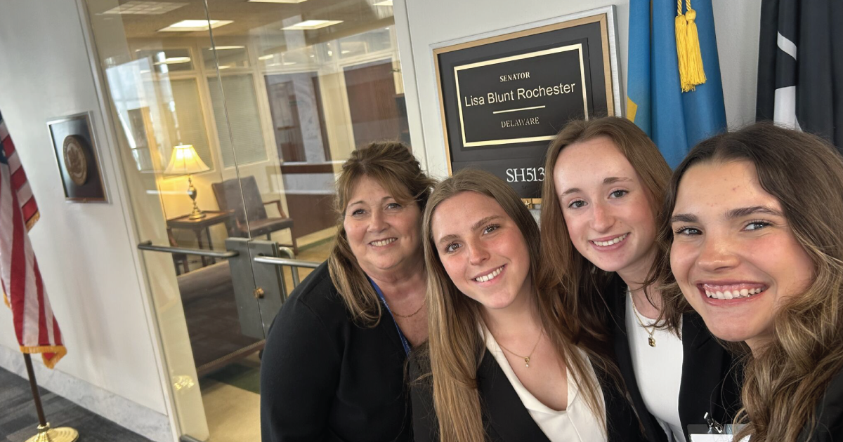 An image of four women at the Capitol Hill building posing in front of an office