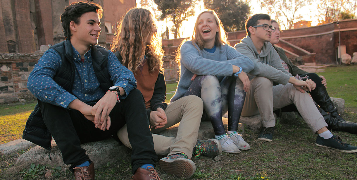 Five UD World Scholars sit in front of the Colosseum during Golden Hour.