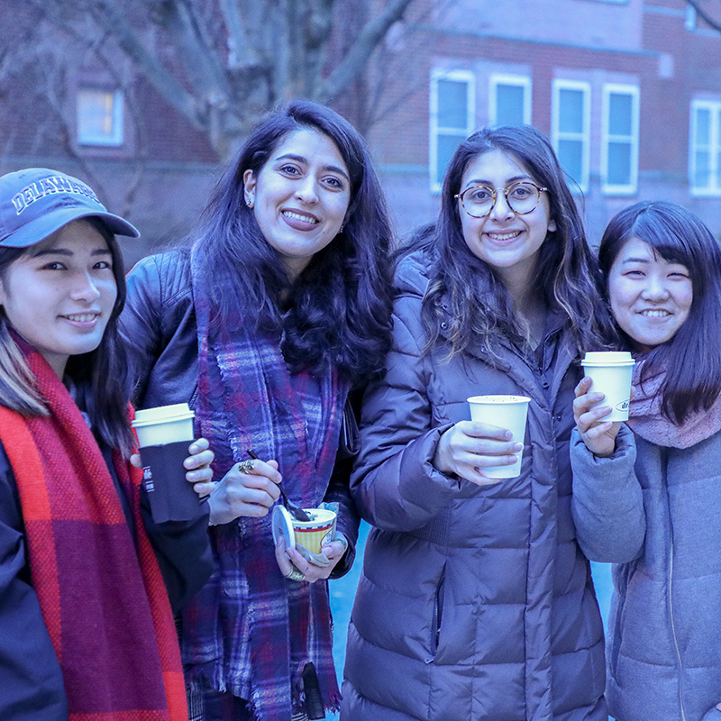 Students pose holding coffee cups at the I Heart iHouse Block Party.