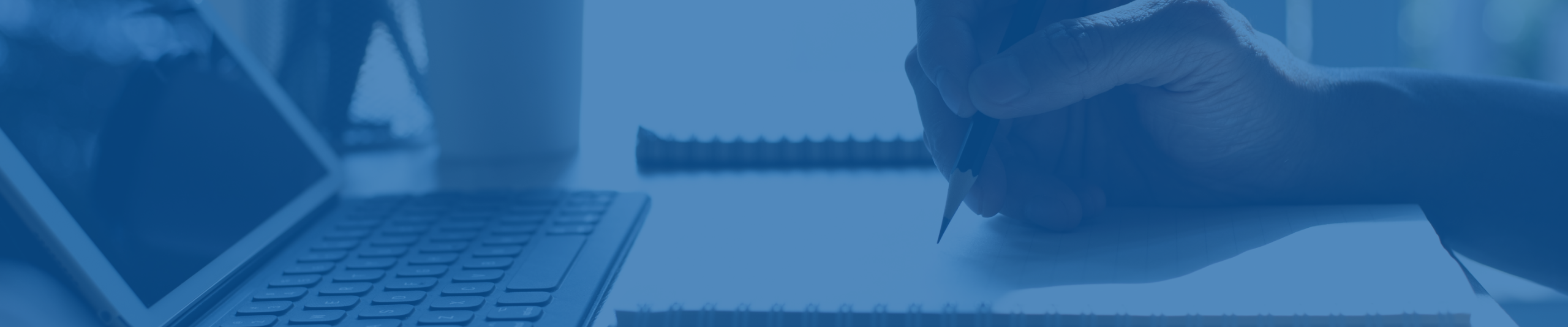 a hand holds a pencil over a blank notepad