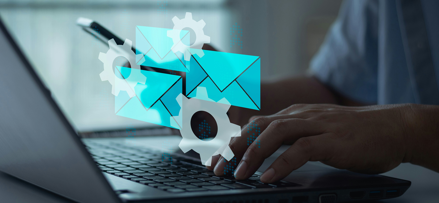 Hands over a laptop keyboard with envelopes and gears glowing on top