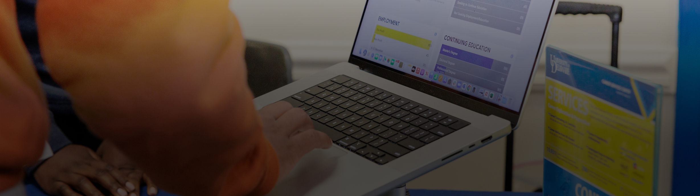 A close up of hands on a laptop, the screen has a chart.