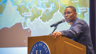 Speaker at a podium with a UD monogram on it.