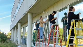 Some people on ladders putting up window decals to help prevent bird strikes.