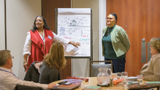 Academy members in a conference room next to a paper flip board.