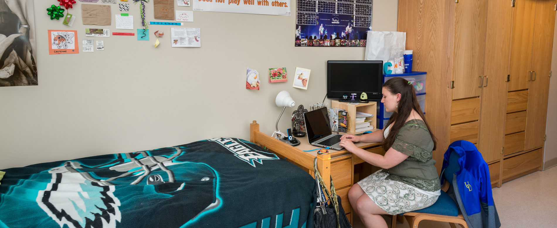 A female student works on a laptop in a dorm in George Read