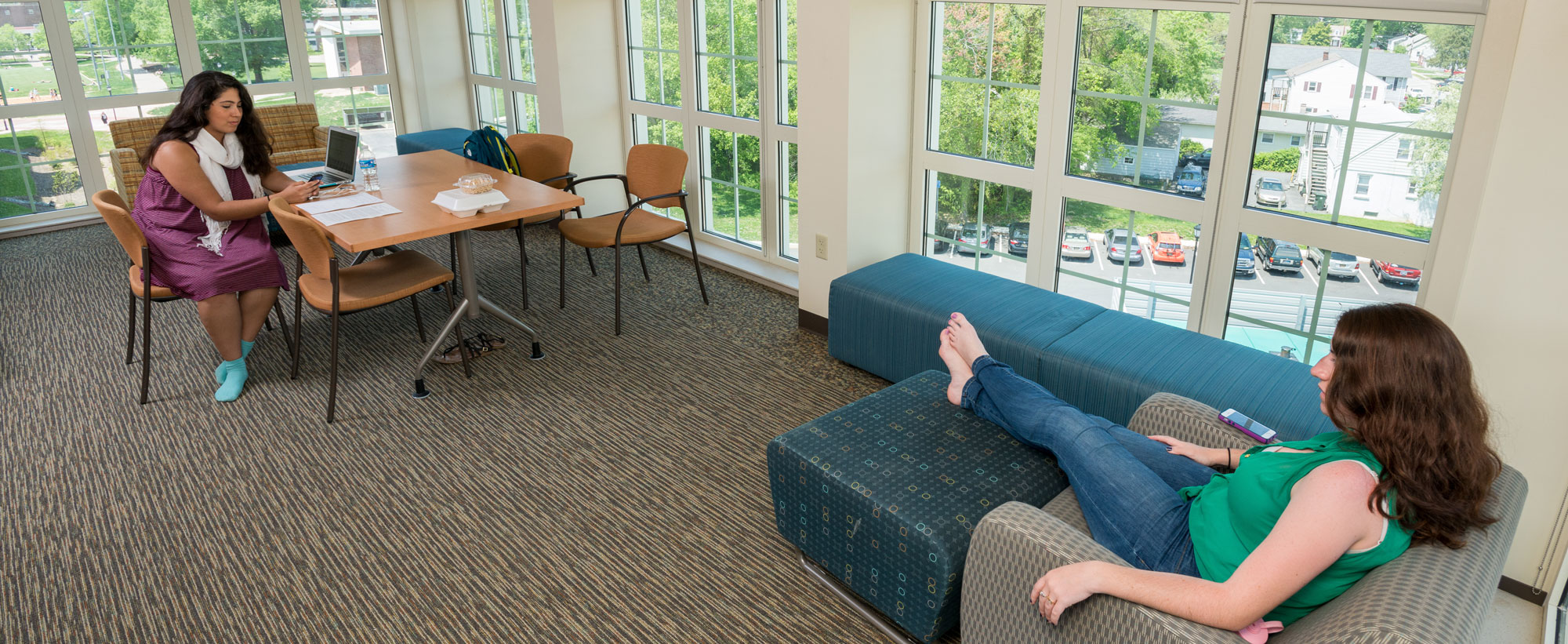 Students relaxing in lounge with comfortable furniture and lots of windows