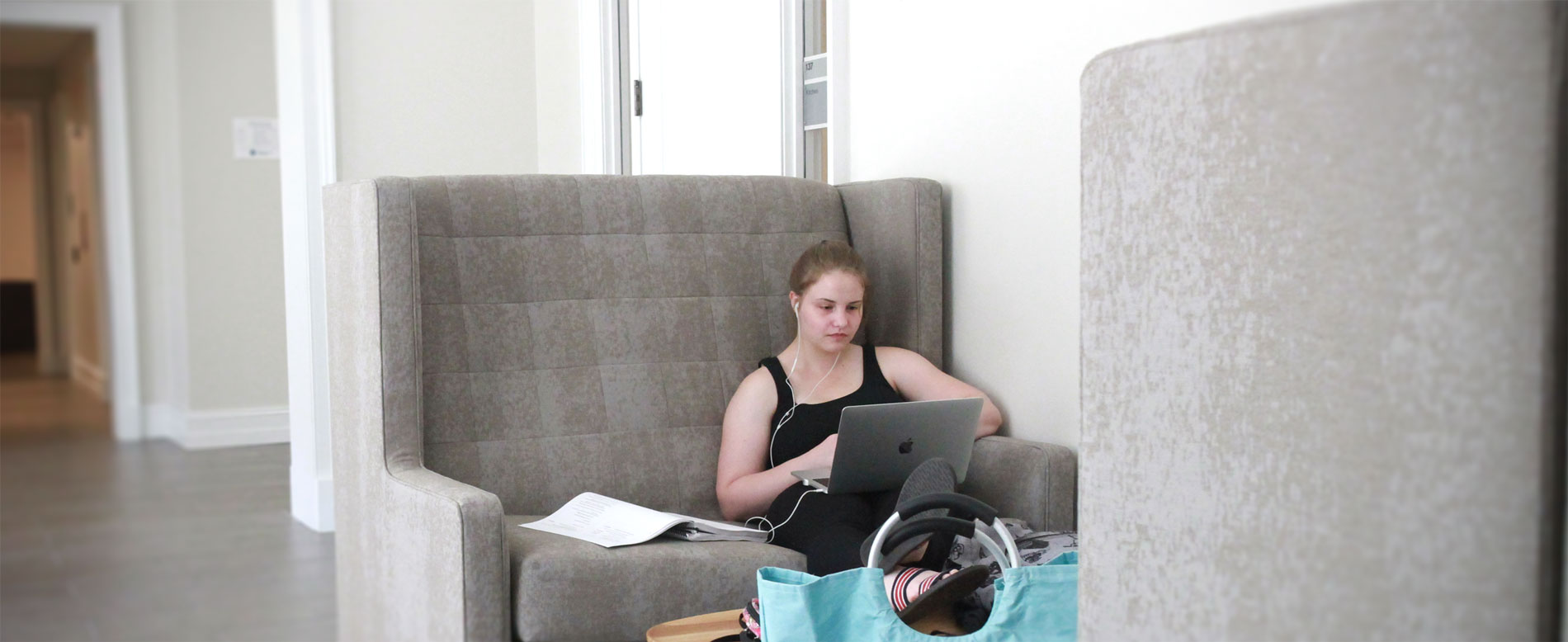 Student sits in high-backed comfortable chair in common area