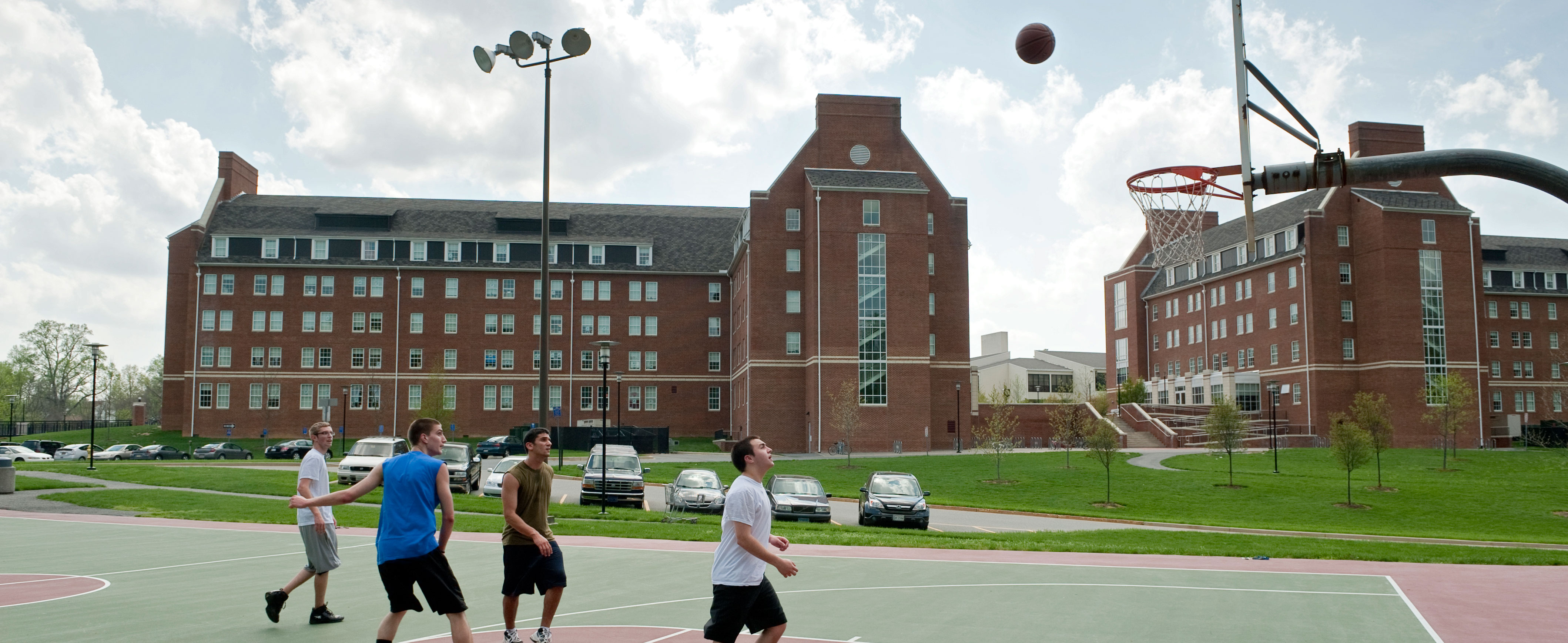 Students playing basketball on a court outside McKean and Smith