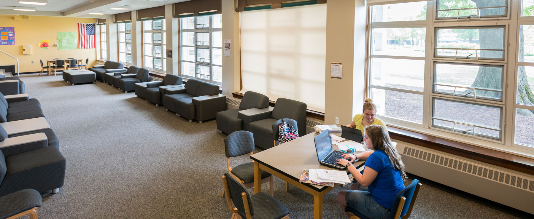 Students study together in a large lounge area with comfortable seating