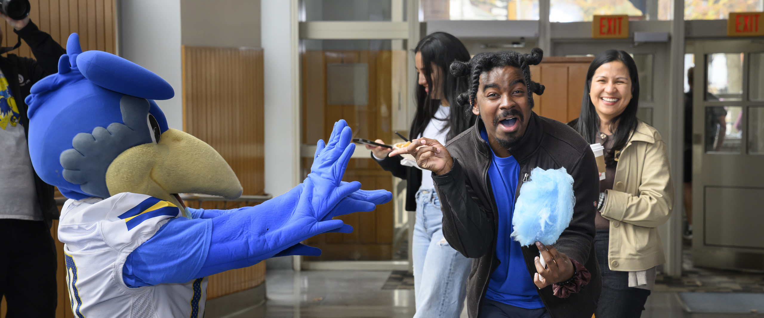 an SDI staff member poses with YouDee and cotton candy at the First-Gen Kickofff