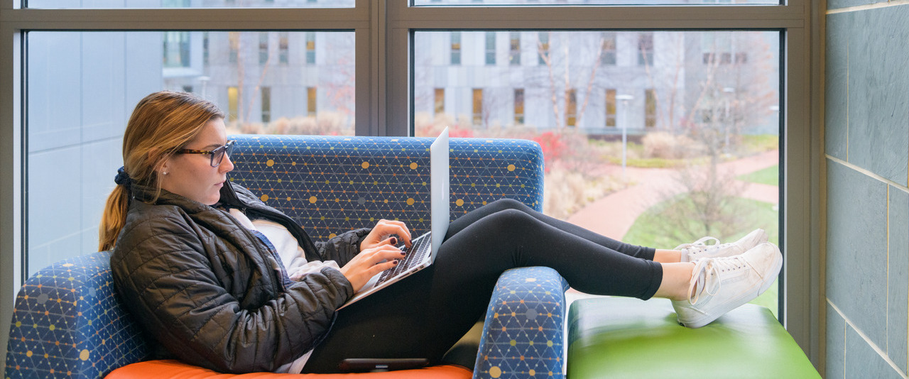 Student lounging in chair with a laptop