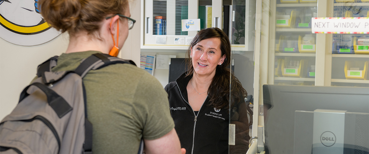 Dispensary employee behind a counter helping a student