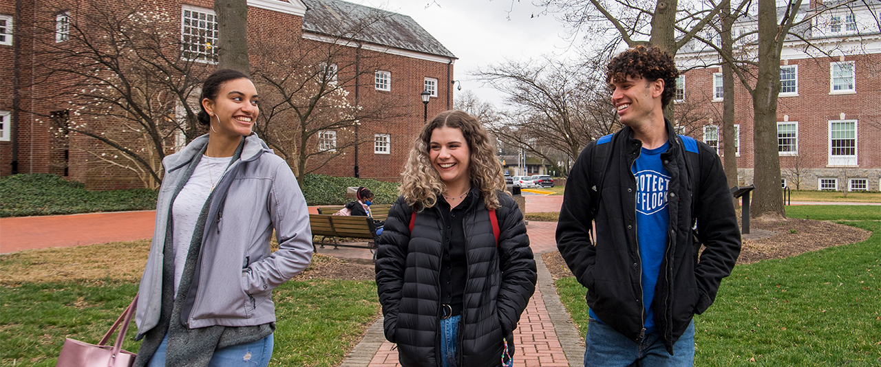 Students walking on the Green, with Student Health Services in the background