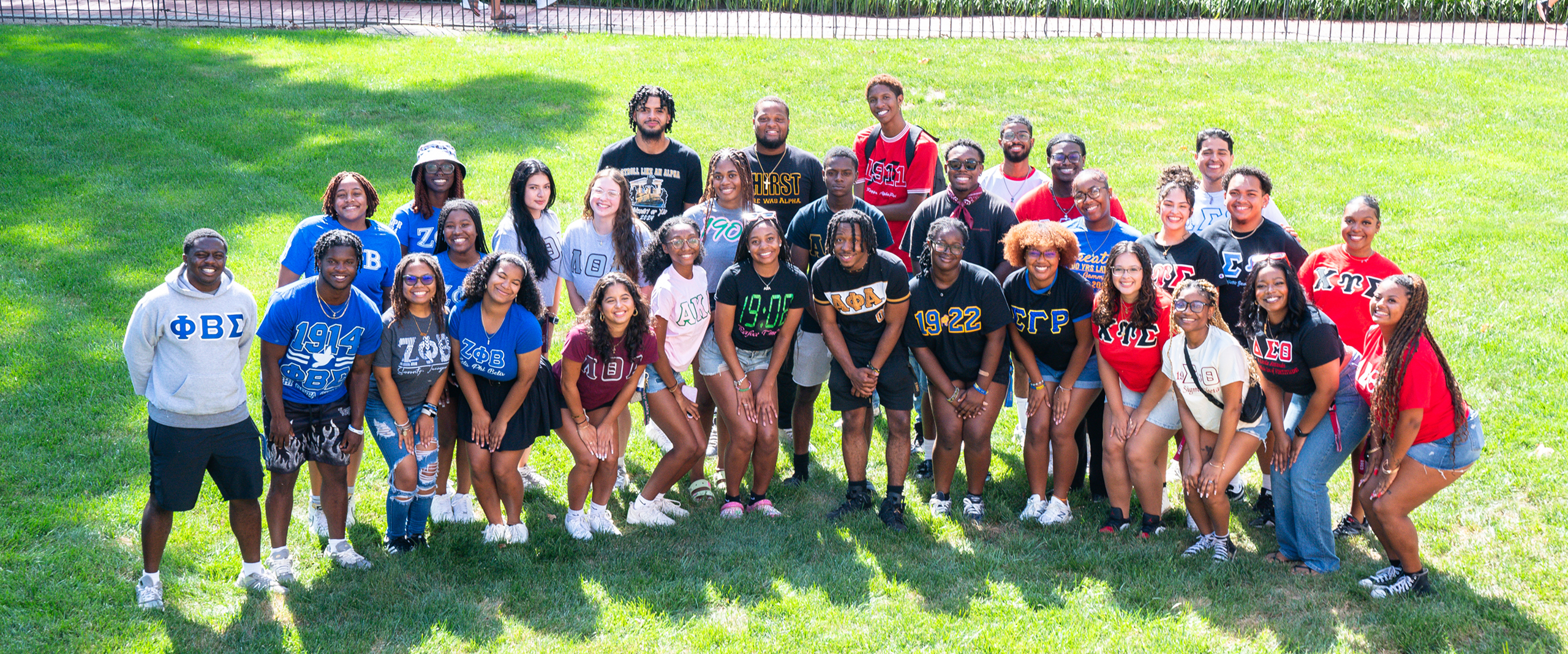 a large group of Greek Life students from chapters in the MGC poses for a picture on a lawn