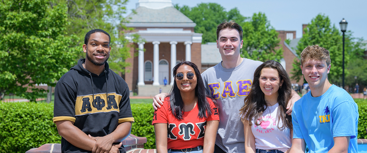 a group of students from UD's fraternities and sororities poses with Memorial Hall in the background