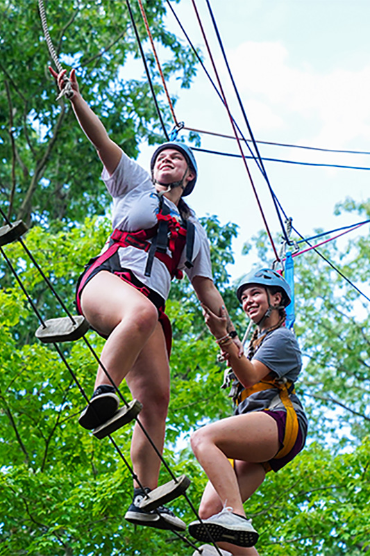 Two students participate in a tree-top ropes course