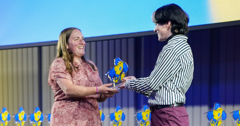 a student accepts her YouDee award from a presenter on stage.
