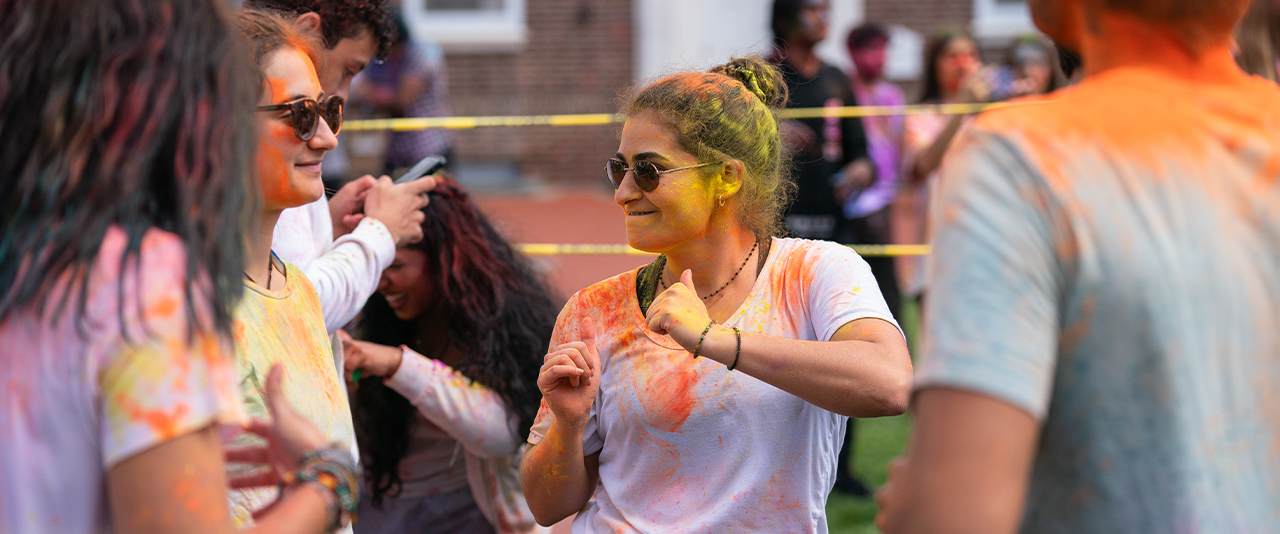 A student covered in colorful chalk dances at the Holi Festival
