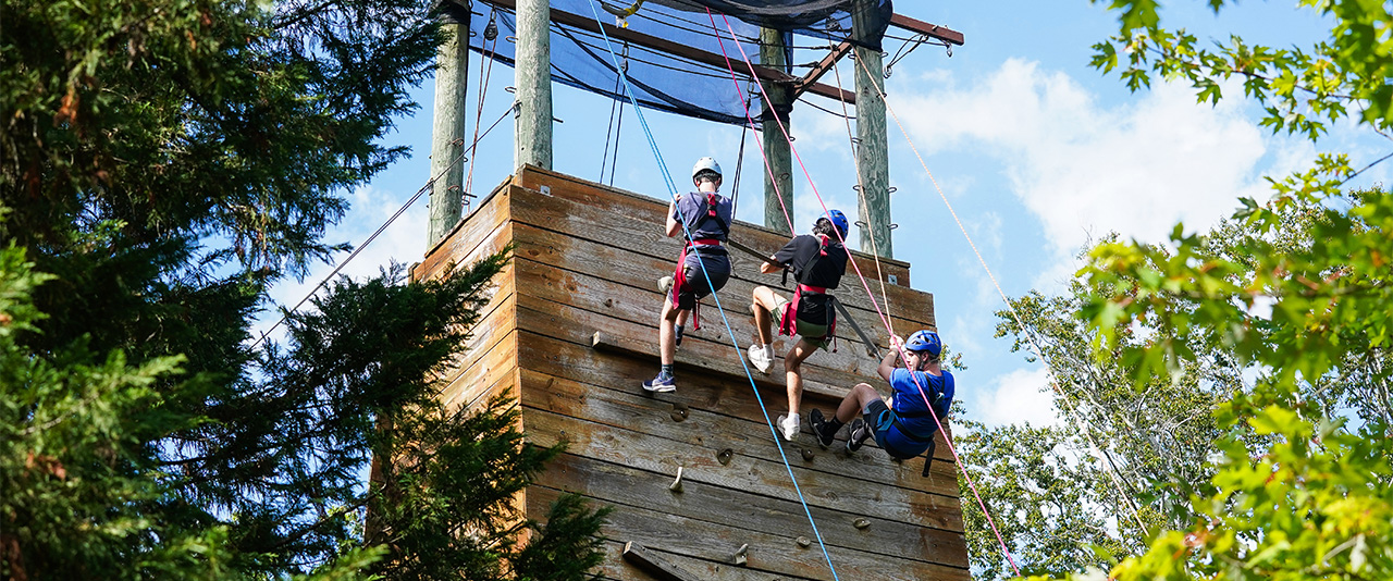 Students climb an outdoor rock wall